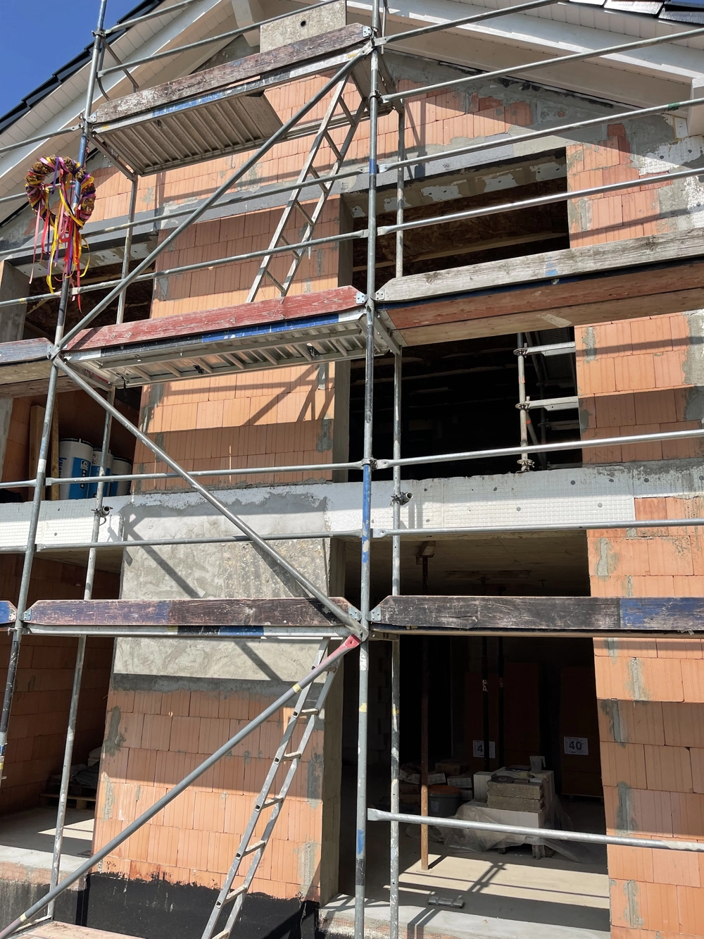 Mehrstöckiges Haus im Rohbau mit Metallgerüst und ungedämmter Backsteinfassade