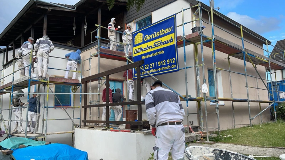 Mehrere Handwerker bei Putzarbeiten an einem Einfamilienhaus mit Gerüst