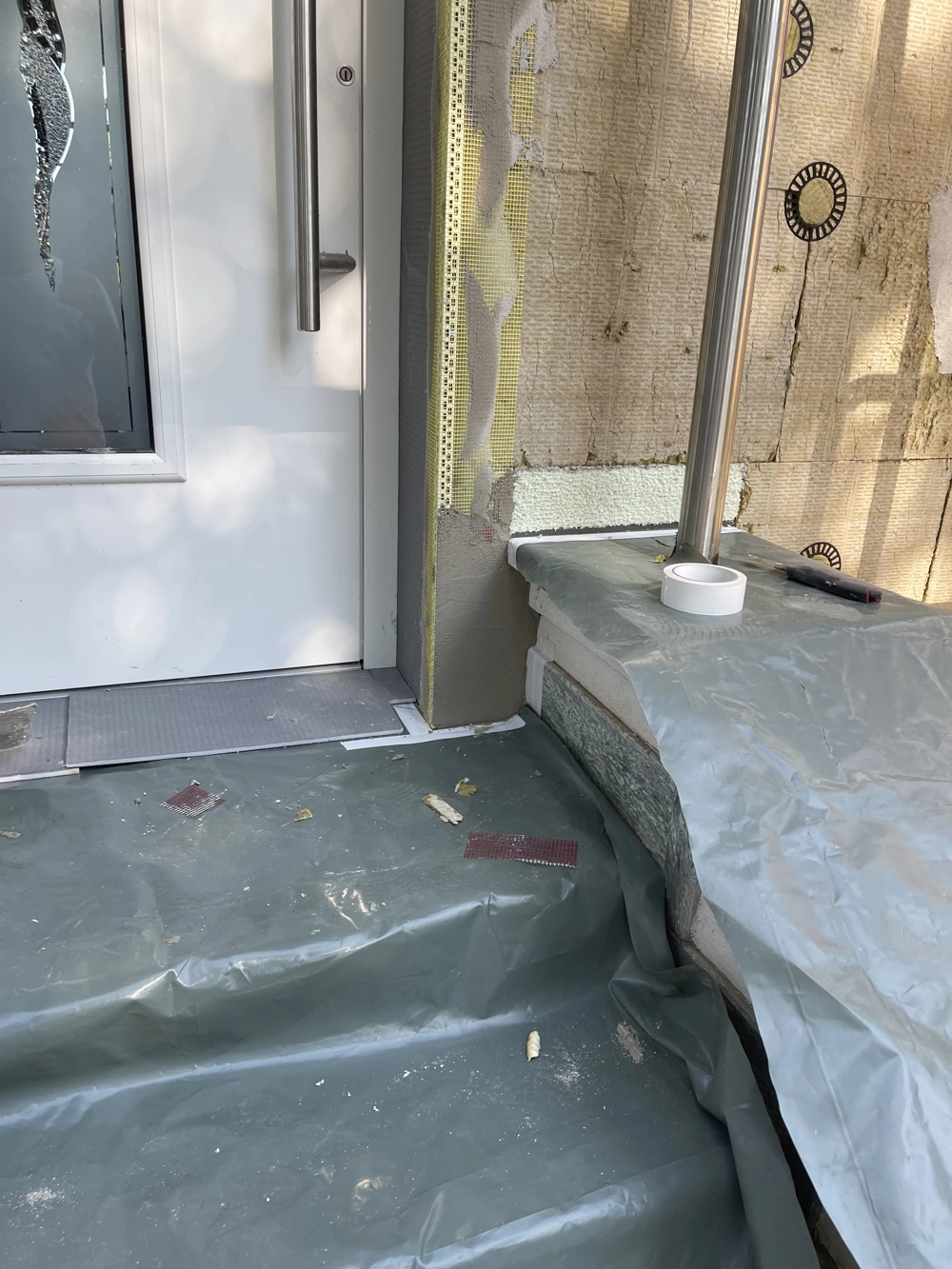 Türenmontage an gedämmter Fassade mit Schutzfolie auf Treppenstufen