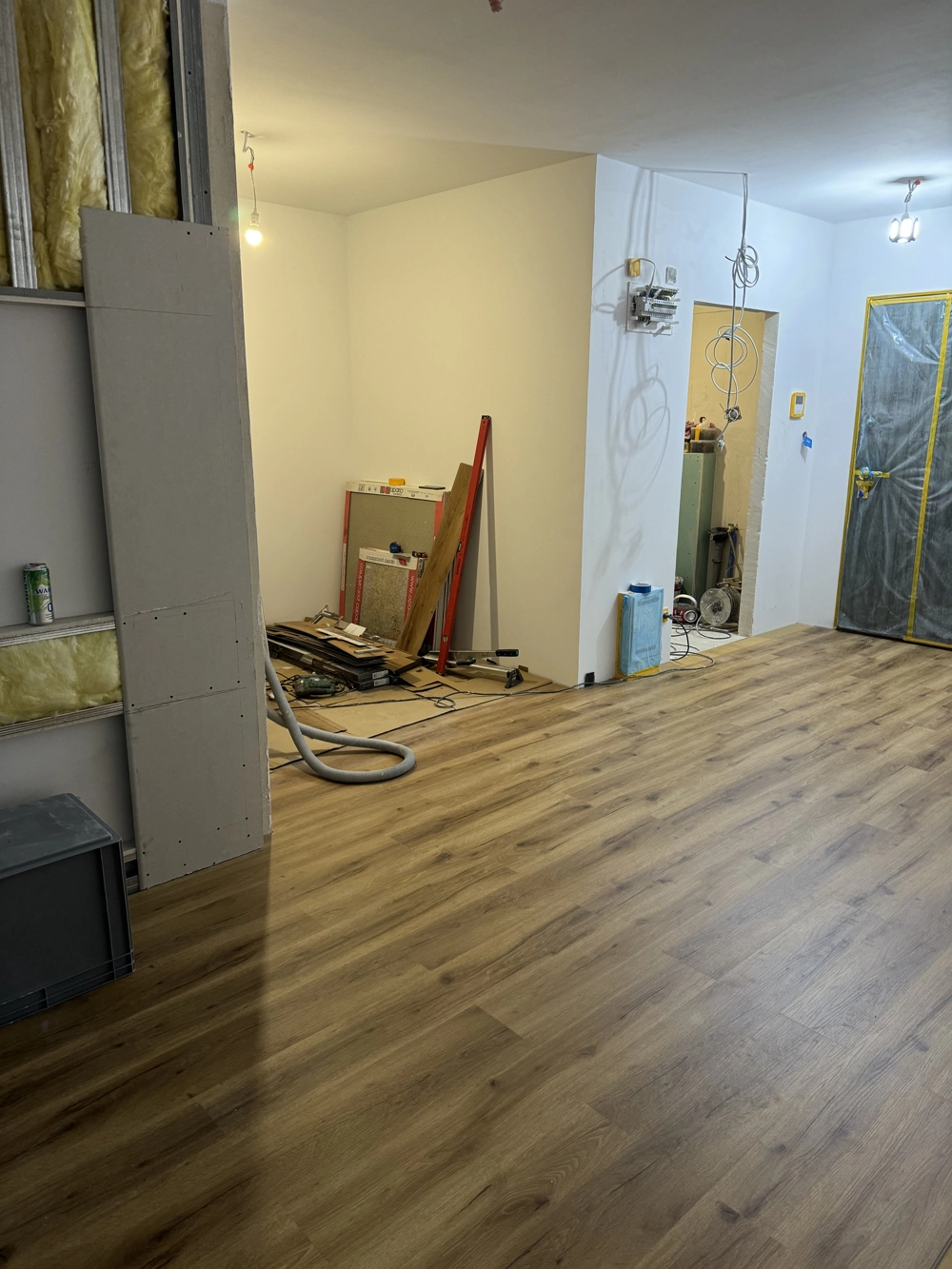 Laminat verlegen – Innenraum mit neu verlegtem Laminatboden, halbfertigen Trockenbauwänden und Werkzeug