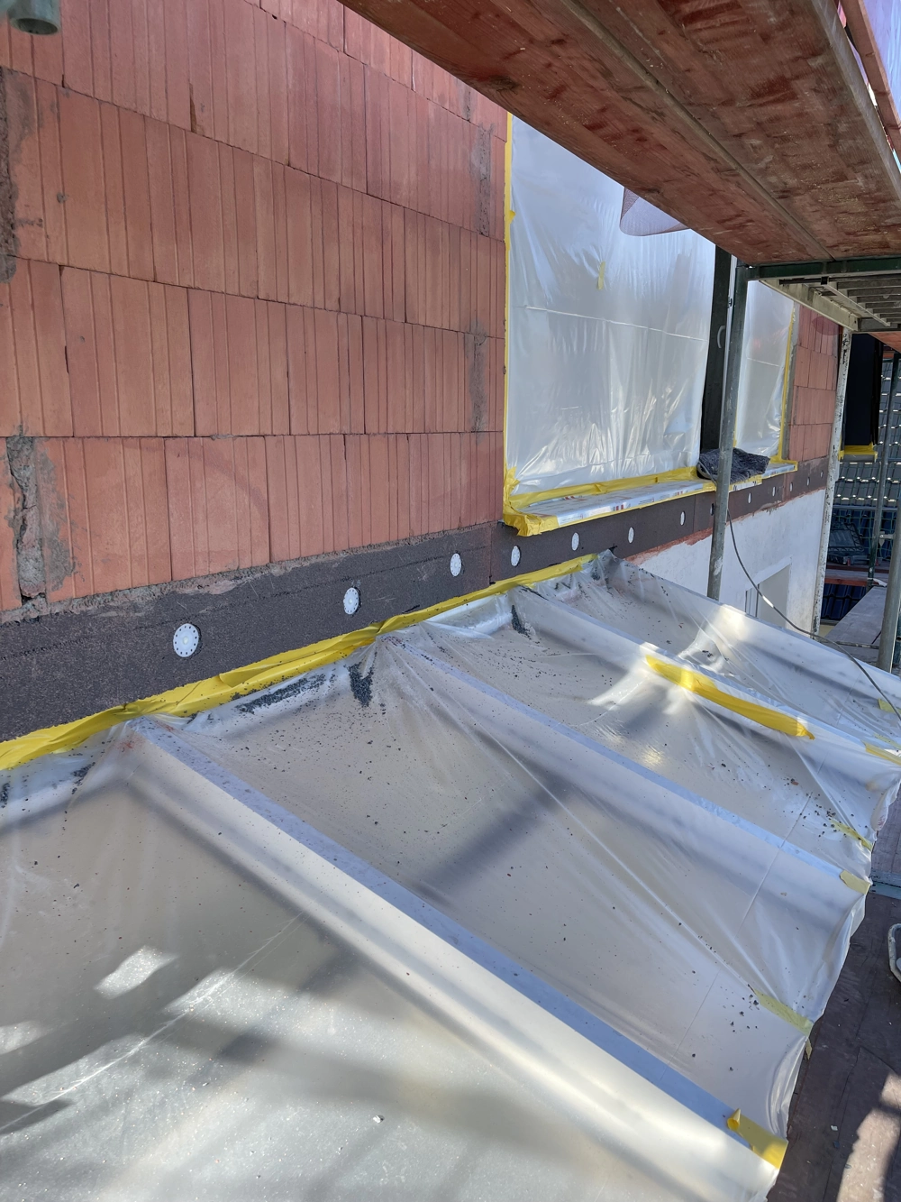 Fassadendämmung mit Putzträgerdämmplatten, Tellerdübeln und abgeklemmten Fensteröffnungen