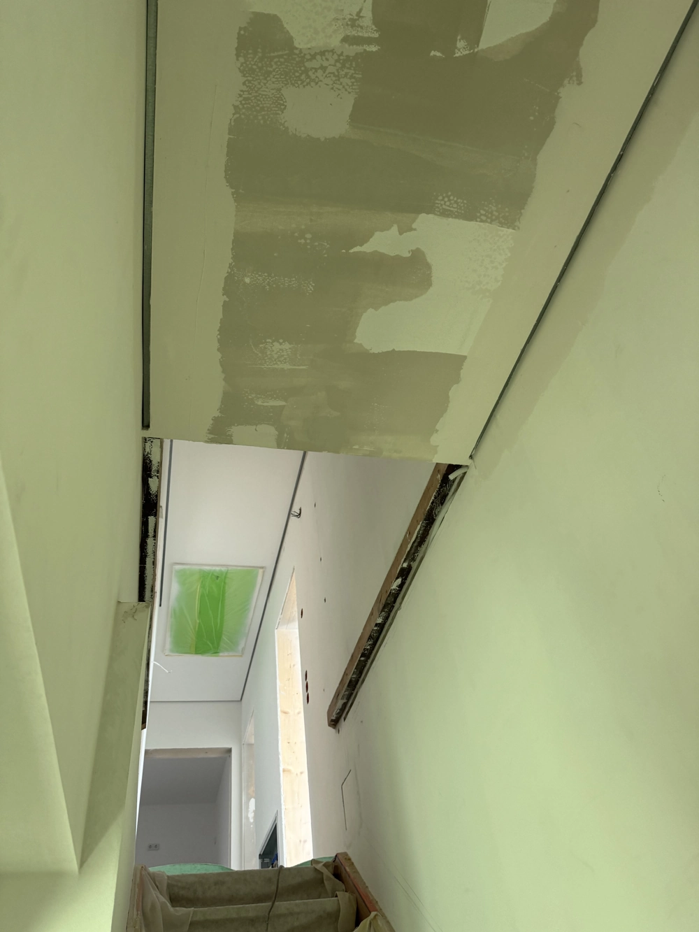 Flur mit abgehängter Decke im Trockenbau: teilweise gespachtelte Gipskartonplatten und vorbereitete LED-Aussparungen