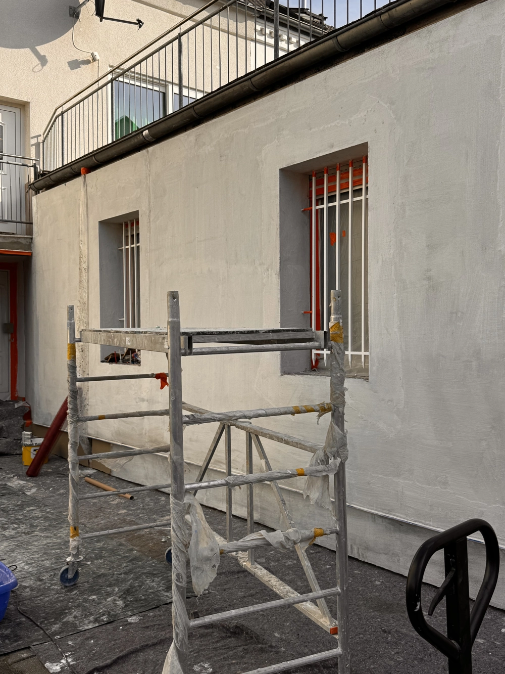 Fahrbares Gerüst vor frisch verputzter Fassade bei Putzarbeiten