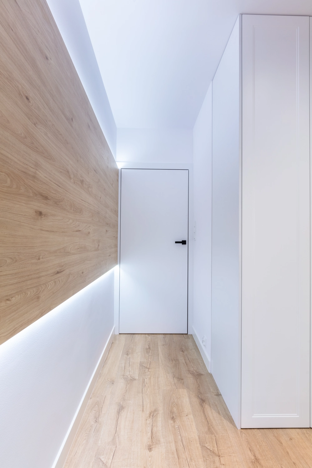 Parkett verlegen im modernen Flur mit hellem Holzfußboden, weißer Tür und minimalistischer Wandverkleidung