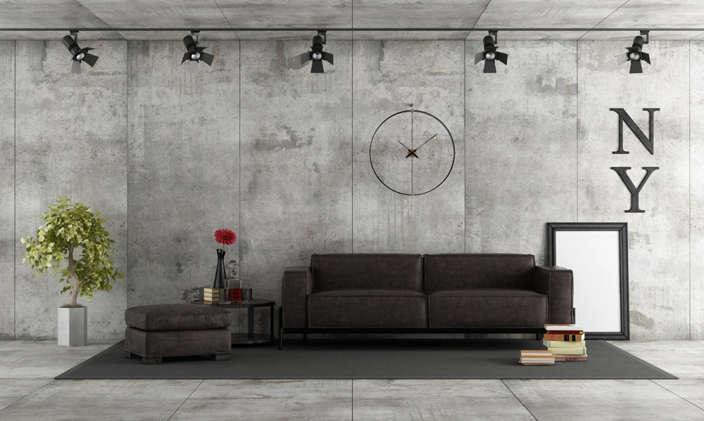 Modernes Wohnzimmer mit freiliegender Sichtbeton Optik an Wänden, schwarzem Ledersofa und Spotbeleuchtung